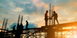 A group of construction workers building a frame structure during sunrise
