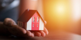 2 hands are holding a house